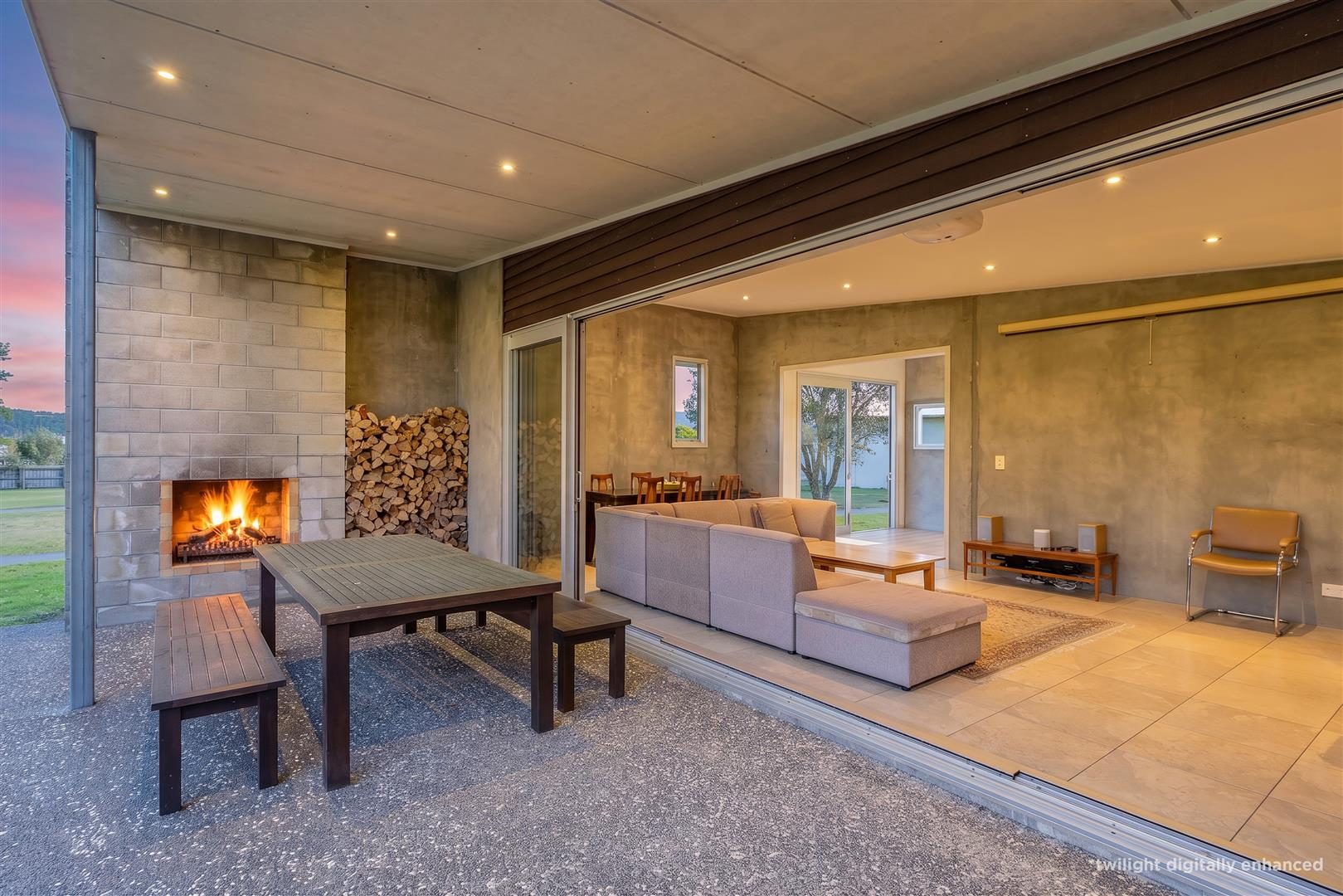 Covered outdoor dining with a lit fireplace opening into the living room